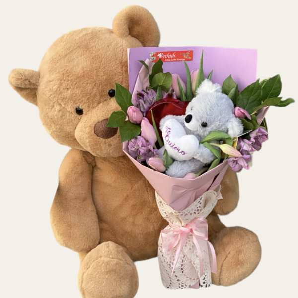 Teddy bear holding a pink bouquet with a small plush bear