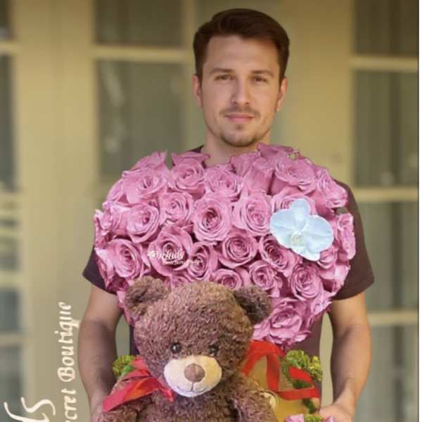 Heart-shaped pink rose arrangement with a teddy bear and ribbon accents