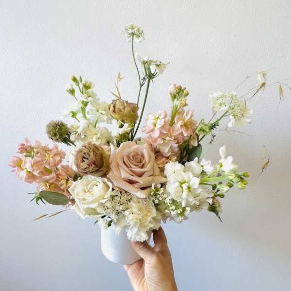Pastel bouquet of roses and white blooms in a white vase