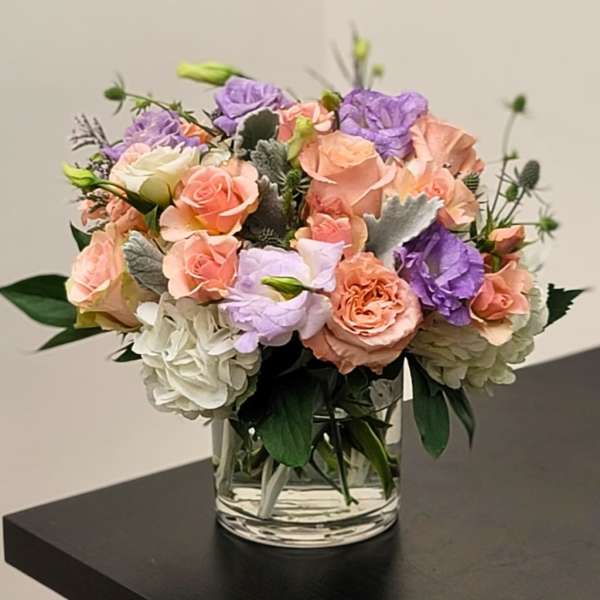 Mixed pastel bouquet of roses and hydrangeas in a clear glass vase