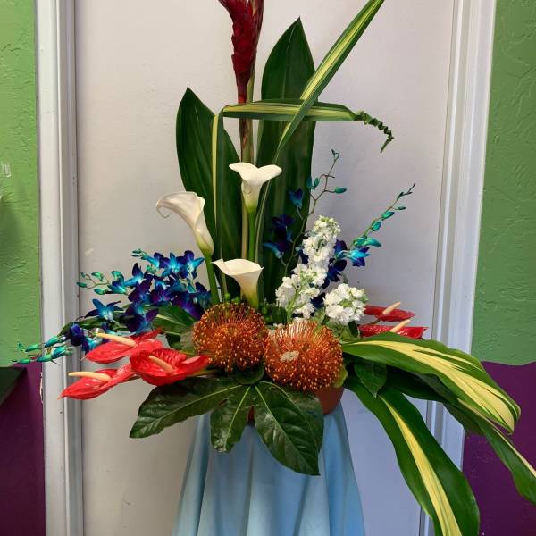 Tropical floral arrangement with red blooms, white calla lilies, and blue orchids