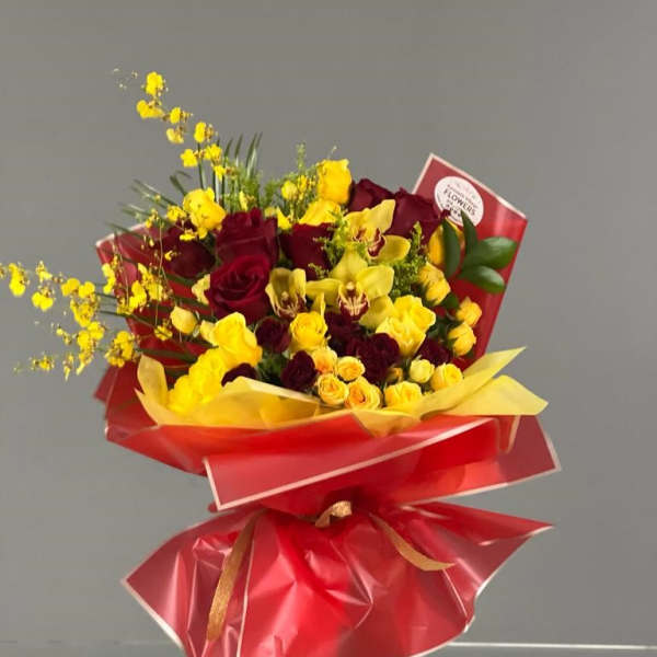 Bouquet of red roses and yellow orchids wrapped in red paper