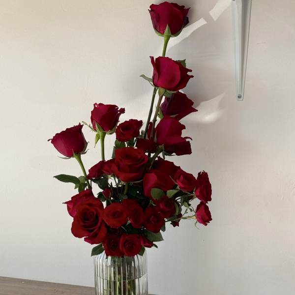 Tall arrangement of red roses in a clear ribbed vase