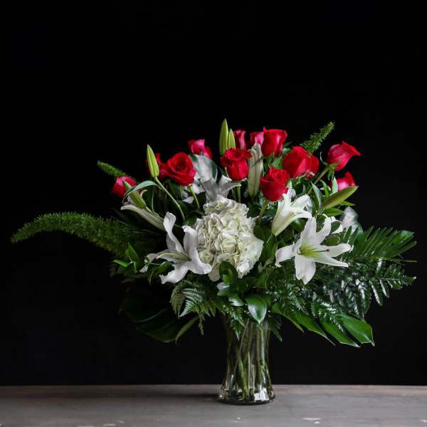 Red roses and white lilies arranged in a clear glass vase