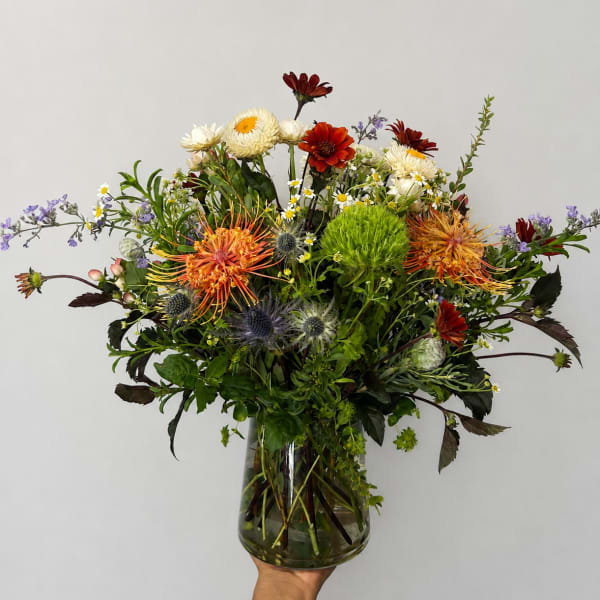 Mixed bouquet in a clear glass vase with orange, white, and red blooms
