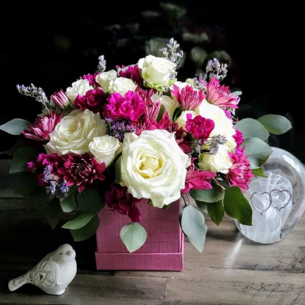 Pink and white rose bouquet in a pink box with a small bird figurine