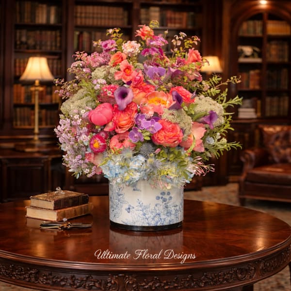 Large mixed flower arrangement in a blue-and-white vase on a wooden table