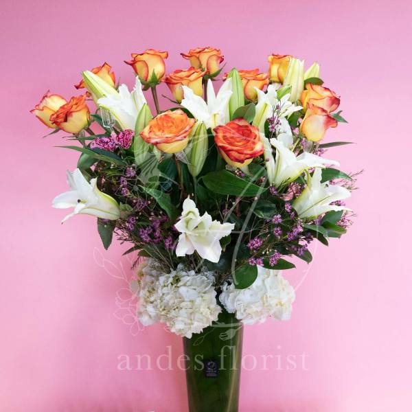 Bouquet of orange-edged roses and white lilies in a tall vase