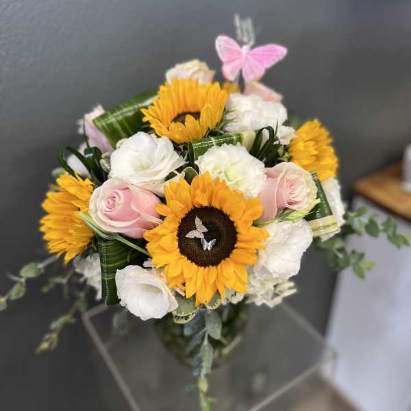 Bouquet of sunflowers, pink roses, and white blooms with a butterfly pick