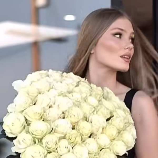 Woman holding a large bouquet of white roses with long ribbon tails