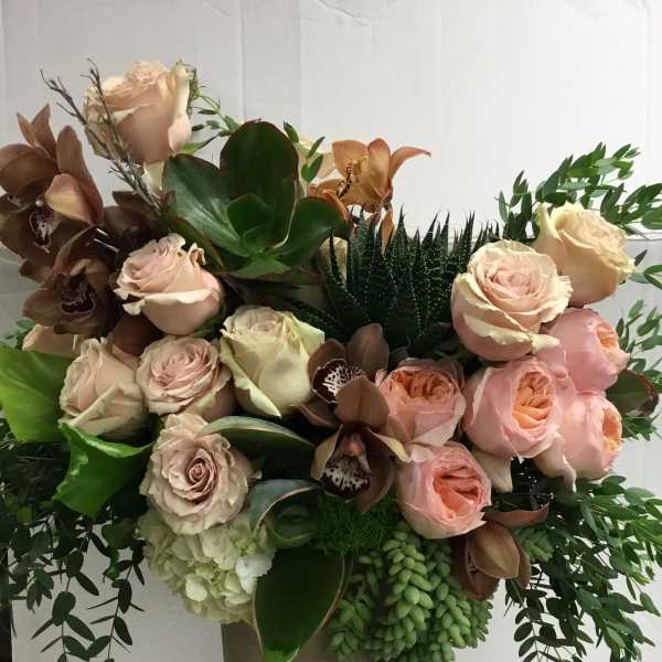 Bouquet of blush roses and orchids in a tall vase