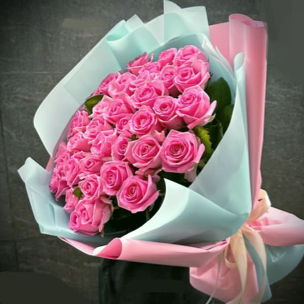 Bouquet of pink roses wrapped in pastel blue and pink paper
