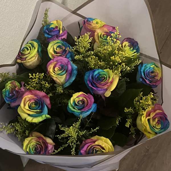 Bouquet of rainbow-colored roses wrapped in white paper