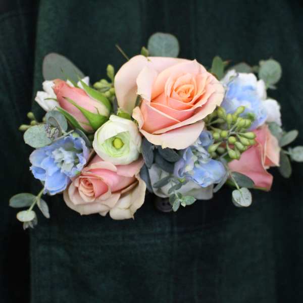 Handheld bouquet of pastel roses and blue flowers with eucalyptus