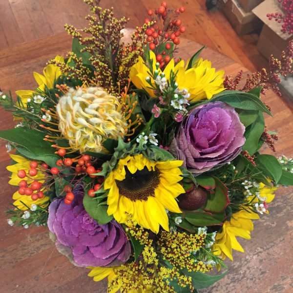 Bouquet with yellow sunflowers, purple ornamental cabbages, and red berry accents