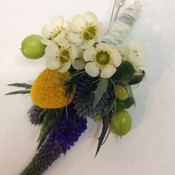 Boutonniere with white blossoms, green berries, and purple accents
