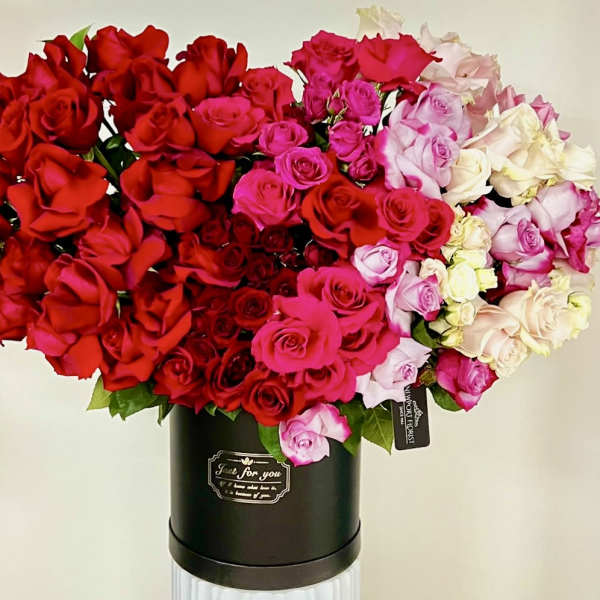 Large bouquet of red, pink, and white roses in a black hatbox