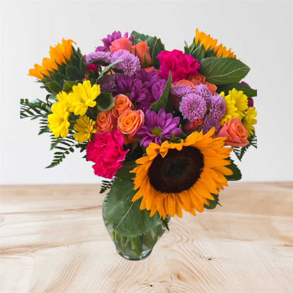 Mixed bouquet with sunflowers, roses, and chrysanthemums in a glass vase