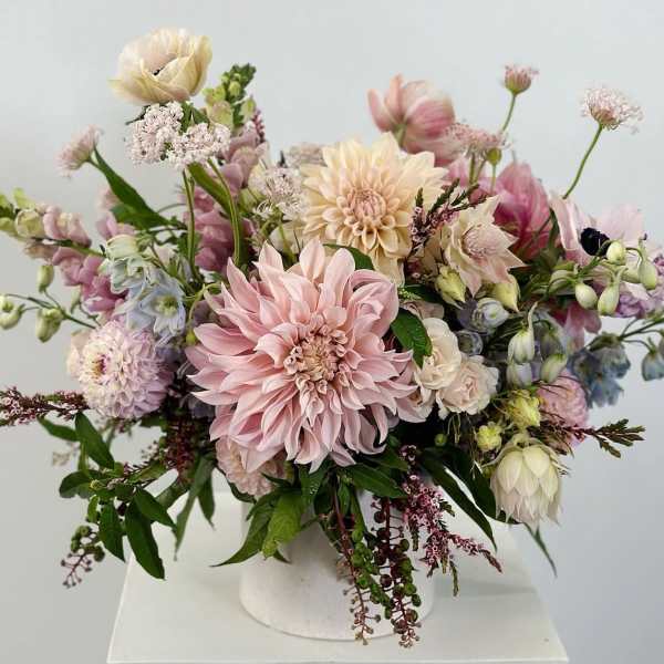 Pastel floral arrangement in a white vase with pink and cream blooms