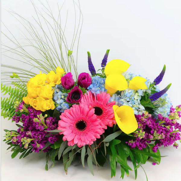 Bright mixed bouquet with pink gerberas, yellow callas, and blue hydrangeas