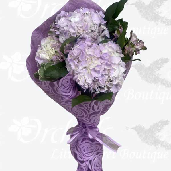 Lavender hydrangea bouquet wrapped in purple paper with a ribbon