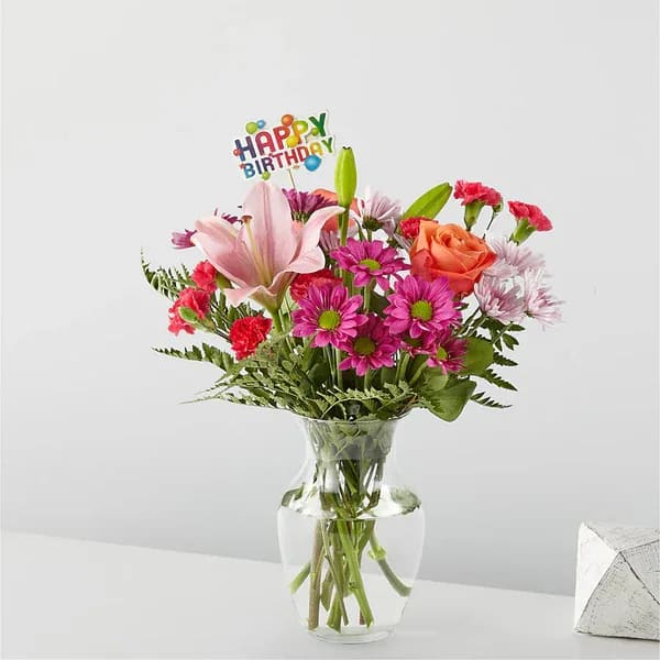 Mixed bouquet in a glass vase with a birthday topper