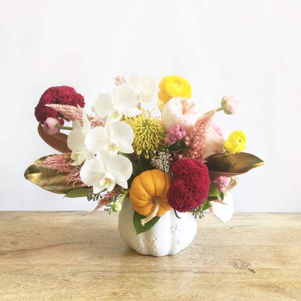 Mixed floral arrangement in a white pumpkin vase with white orchids and yellow blooms