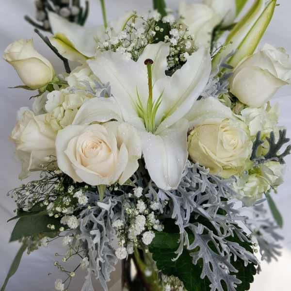 White lilies and roses arranged in a glass vase