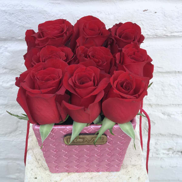 Red roses arranged in a pink textured box