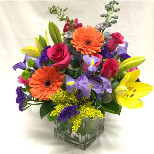 Colorful bouquet of roses, lilies, and gerbera daisies in a glass vase