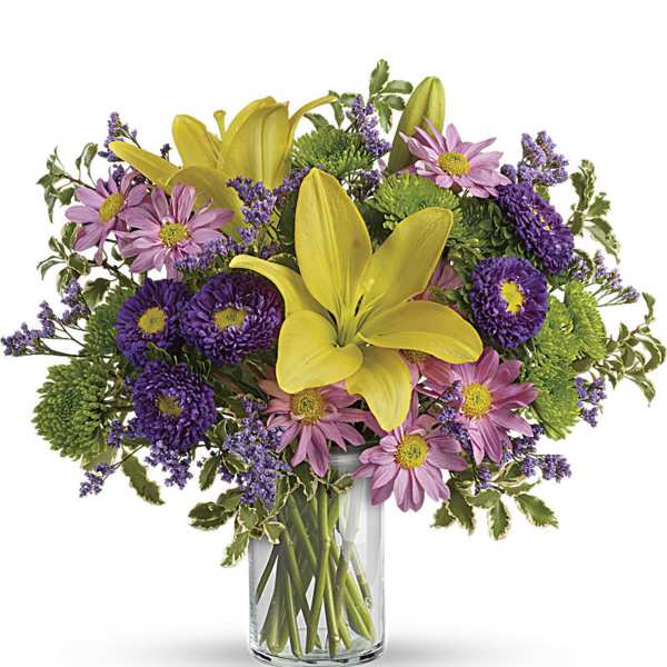 Yellow lilies and pink daisies in a clear glass vase