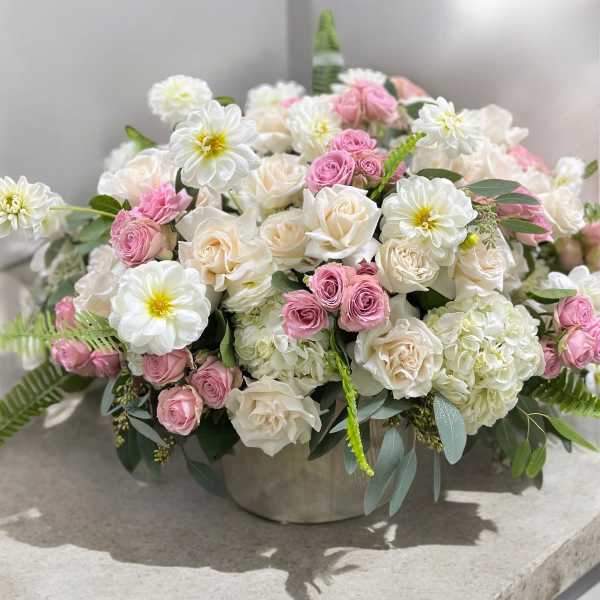 Pink and white roses with white daisies in a low round vase