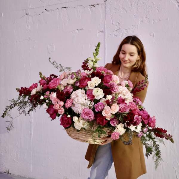 Woman holding a large basket of pink and white flowers