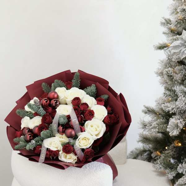 Bouquet of red and white roses with ornaments and evergreen sprigs