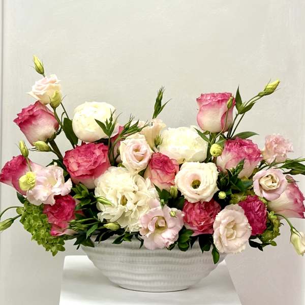 Pink and white floral arrangement in a white bowl vase