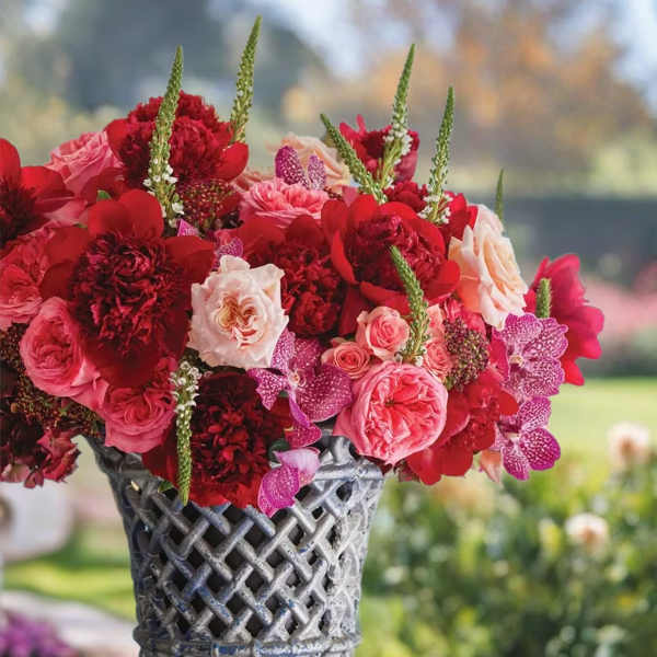 Red and pink floral arrangement in a decorative metal vase