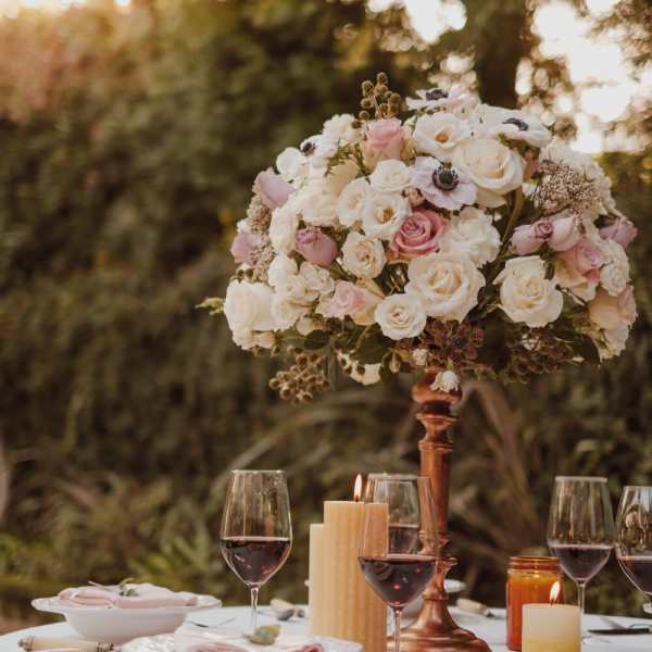 Pink and white rose centerpiece on a copper stand at a candlelit table