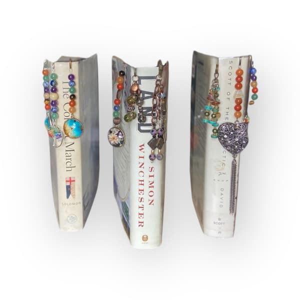 Three decorated book spines with beaded charms hanging from them