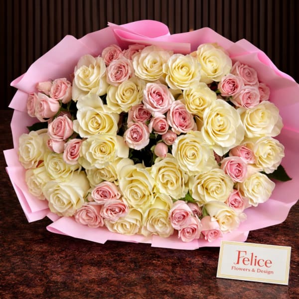 Bouquet of cream and pink roses wrapped in pink paper