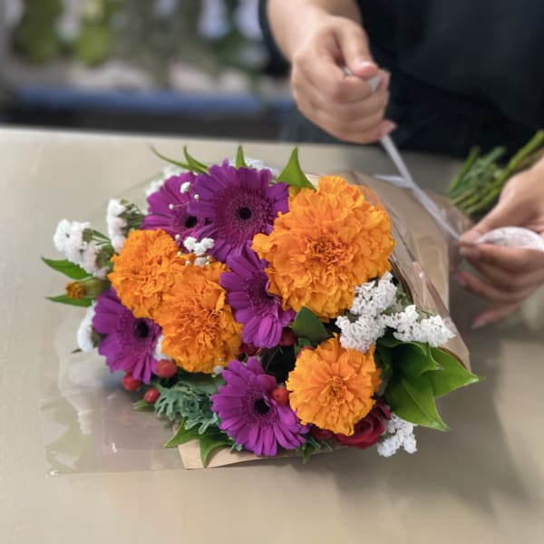 Bouquet of purple gerbera daisies and orange marigolds wrapped in paper