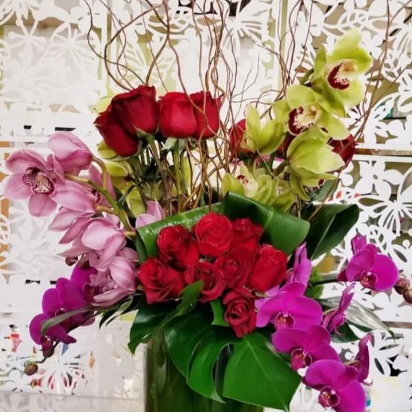 Mixed bouquet of red roses and orchids in a green vase