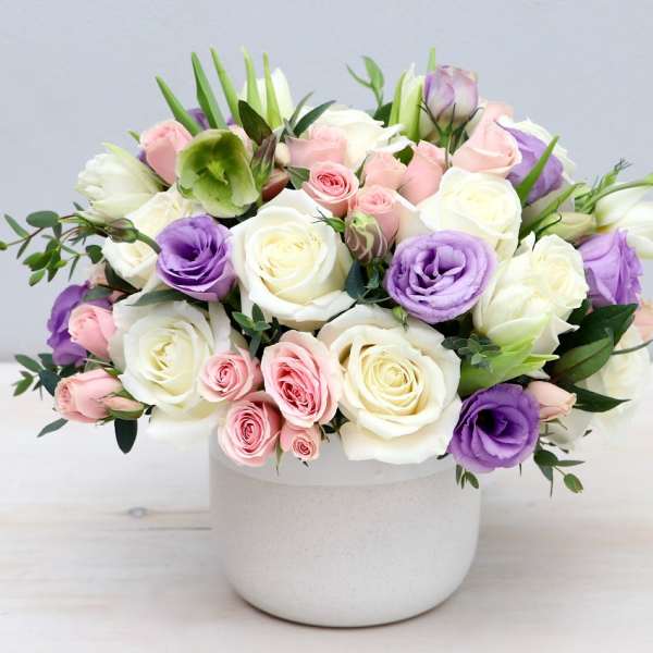 Bouquet of white, pink, and purple roses in a white vase