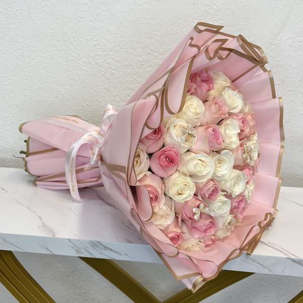 Pink and white rose bouquet wrapped in pink paper with gold trim