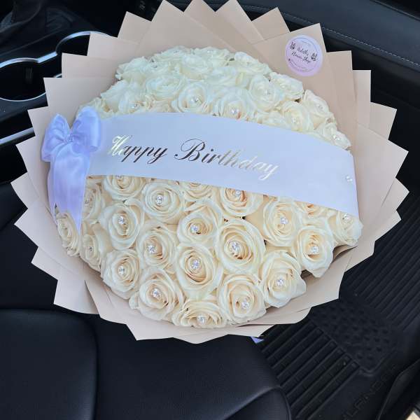 Cream rose bouquet with a Happy Birthday ribbon in a car seat