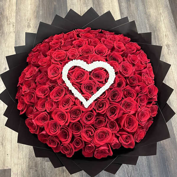 Round bouquet of red roses with a white heart accent