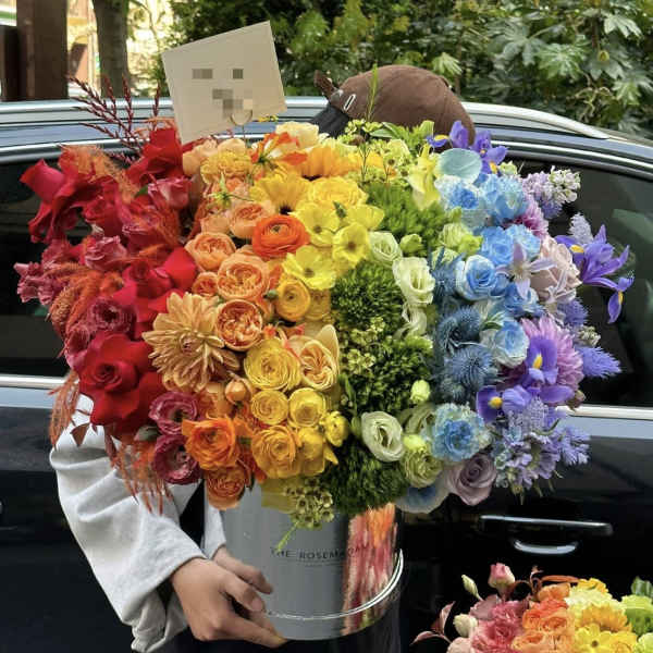 Large rainbow bouquet in a silver bucket held by a person
