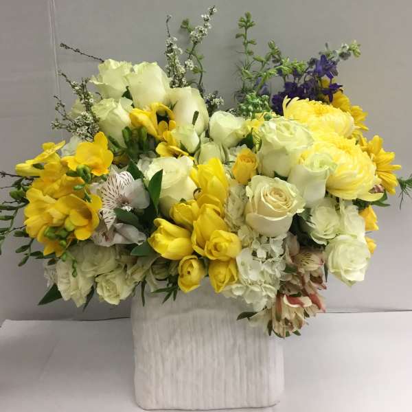 Yellow and white mixed flower arrangement in a white vase