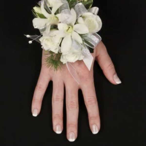White floral wrist corsage with ribbon on a hand