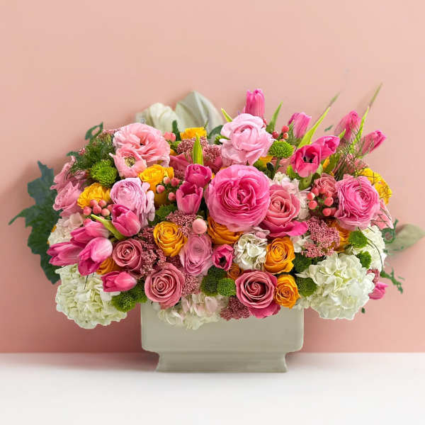 Pink and yellow mixed flower arrangement in a rectangular vase