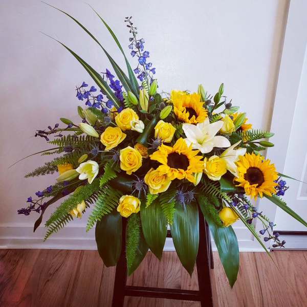 Yellow roses, sunflowers, and white lilies in a low arrangement